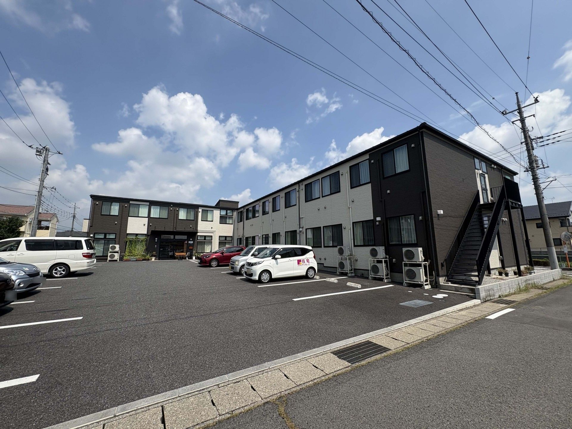 コップを持って微笑んでいるエプロンを付けた女性スタッフ。そばには薬を飲もうとしている高齢女性がいる。