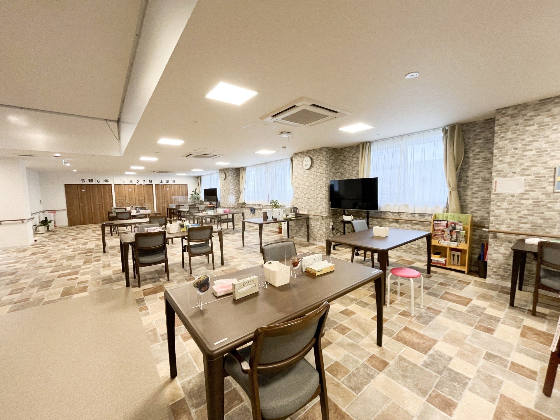 フローリングの部屋にはラグが敷かれ、寝具付きのベッドやテーブルセットがあり、ベッドサイドには緊急通報装置がある。
