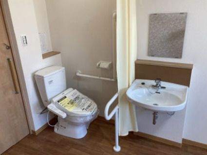 カーテンで開け閉めするタイプのトイレと車いす対応の洗面所が付いた居室。