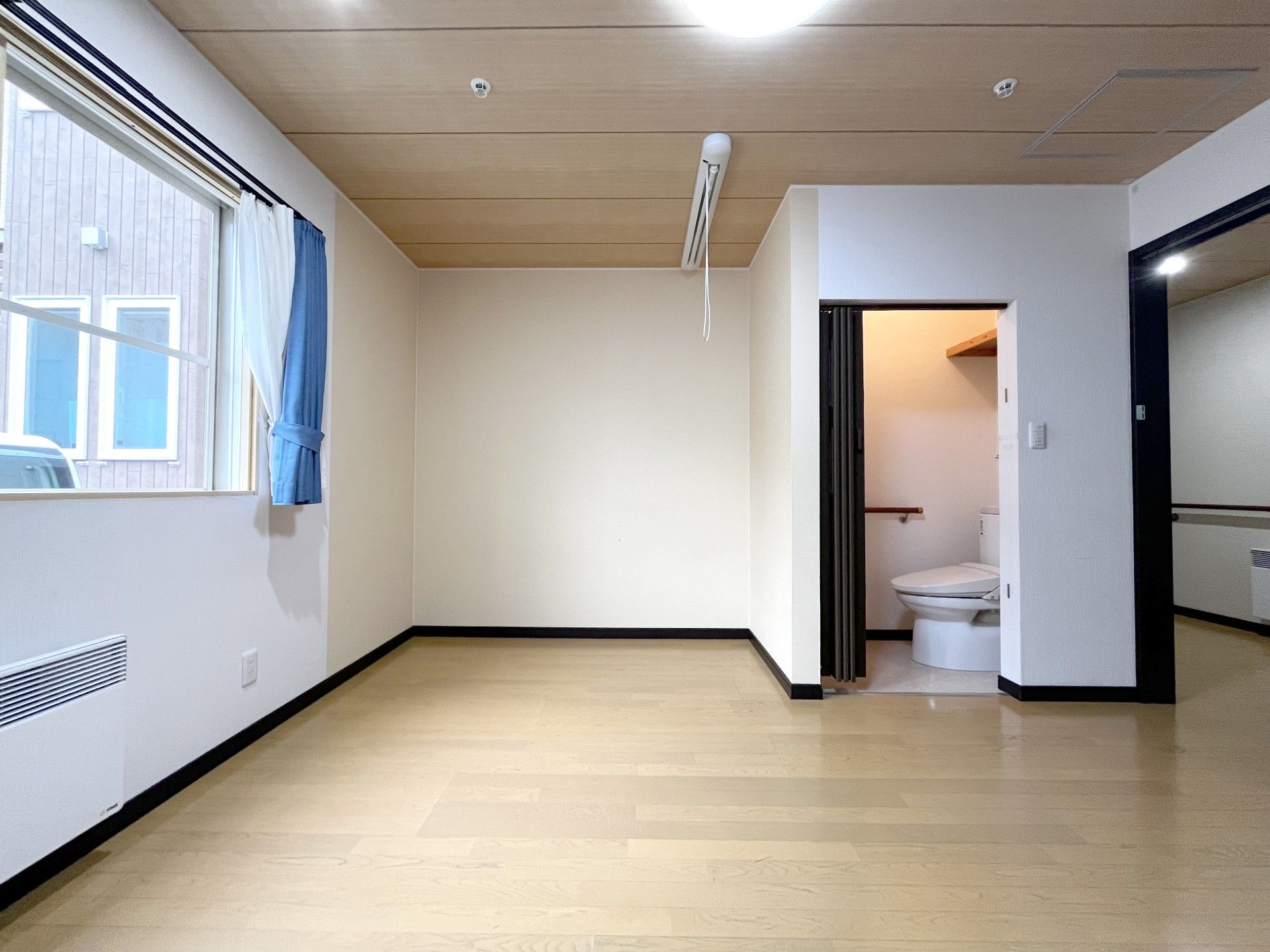 遠くを指さして笑顔でいる車いすの高齢女性とエプロンを付けた女性スタッフ。