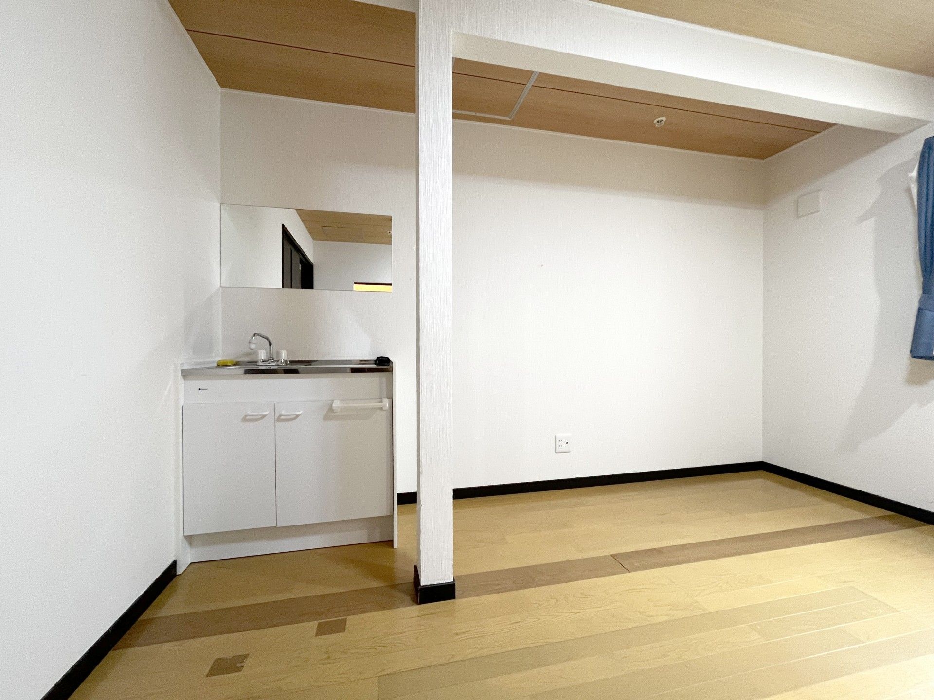 ピンクのエプロンを付けた若い女性スタッフとカーディガンを着た車いすの高齢女性が笑顔でおしゃべりをしている。