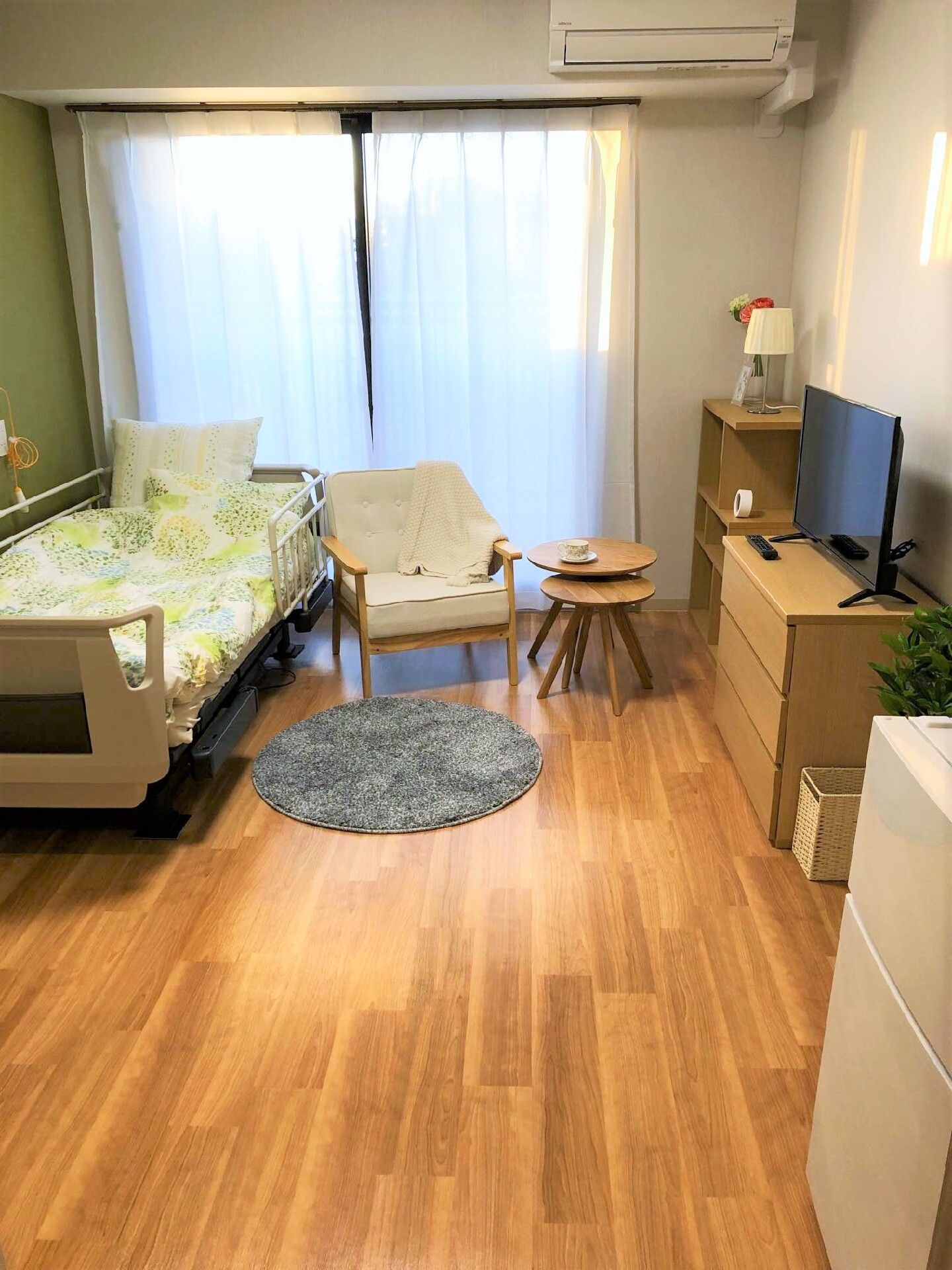 グリーンの屋根が付いた5階建ての建物には屋外階段も設置されている。周りには民家があり、緑も多い。