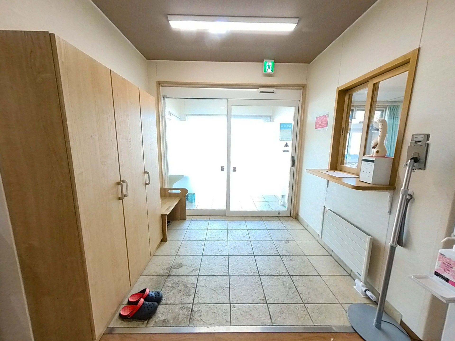 白髪女性の肩にタオルをかけながら微笑みかけている紺のポロシャツを着た女性スタッフ。