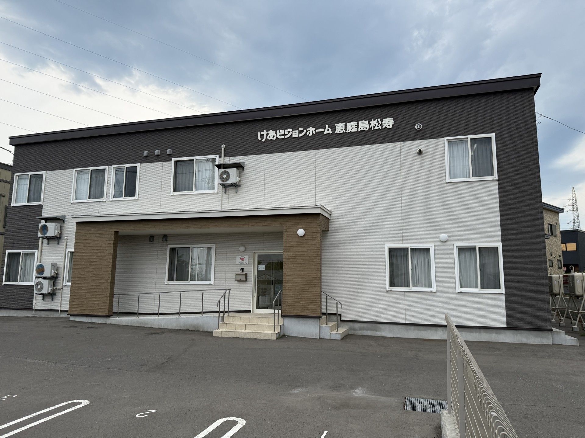 薬を飲もうとしている高齢女性と水の入ったコップを持って微笑んでいるエプロンを付けた女性スタッフ。