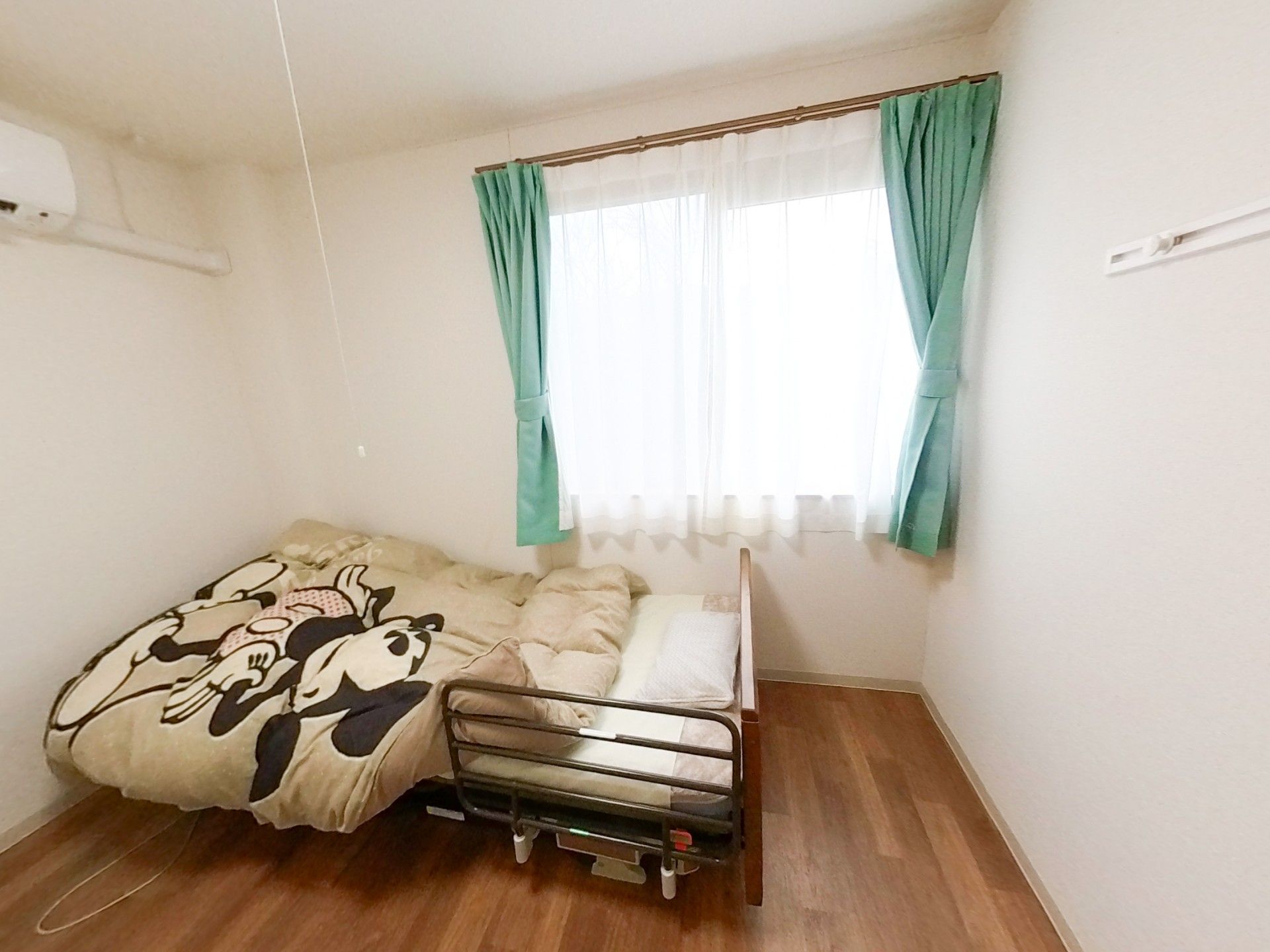 遠くを笑顔で指さし笑っている車いすの高齢女性とエプロンを付けた女性スタッフ。