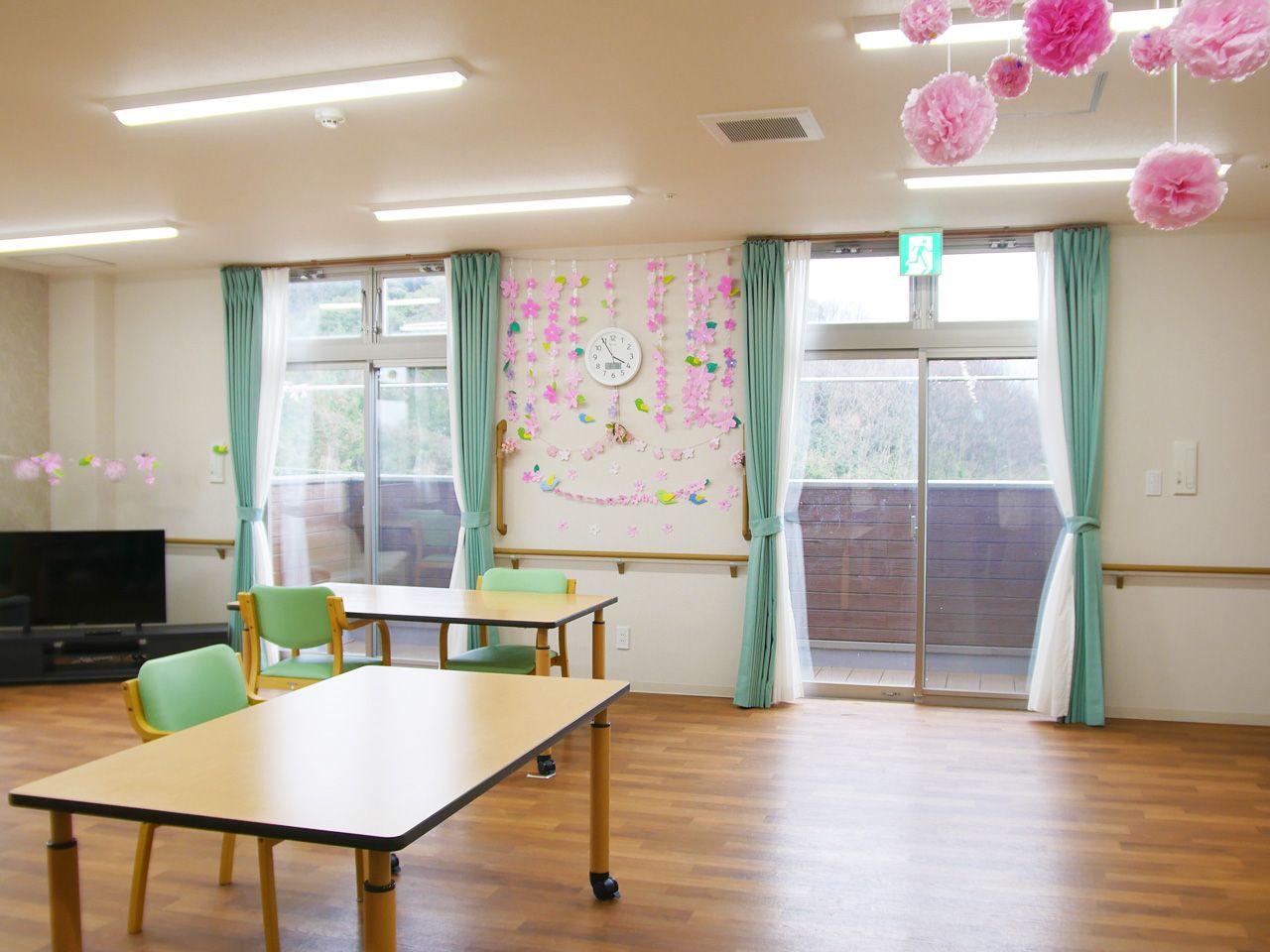 屋外で過ごす車いすの高齢男性に付き添っているポロシャツを着た女性スタッフ。笑顔で話している。