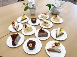 応答、メロンなどのフルーツが乗ったケーキやチョコレートケーキ、クマの顔の形のケーキなどが白い皿に盛られて並んでいる。