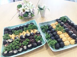 黒や茶色、ベージュの丸いおはぎのようなものが二つの四角い皿にたくさん並べられている。彩りとしてパセリも添えられている。