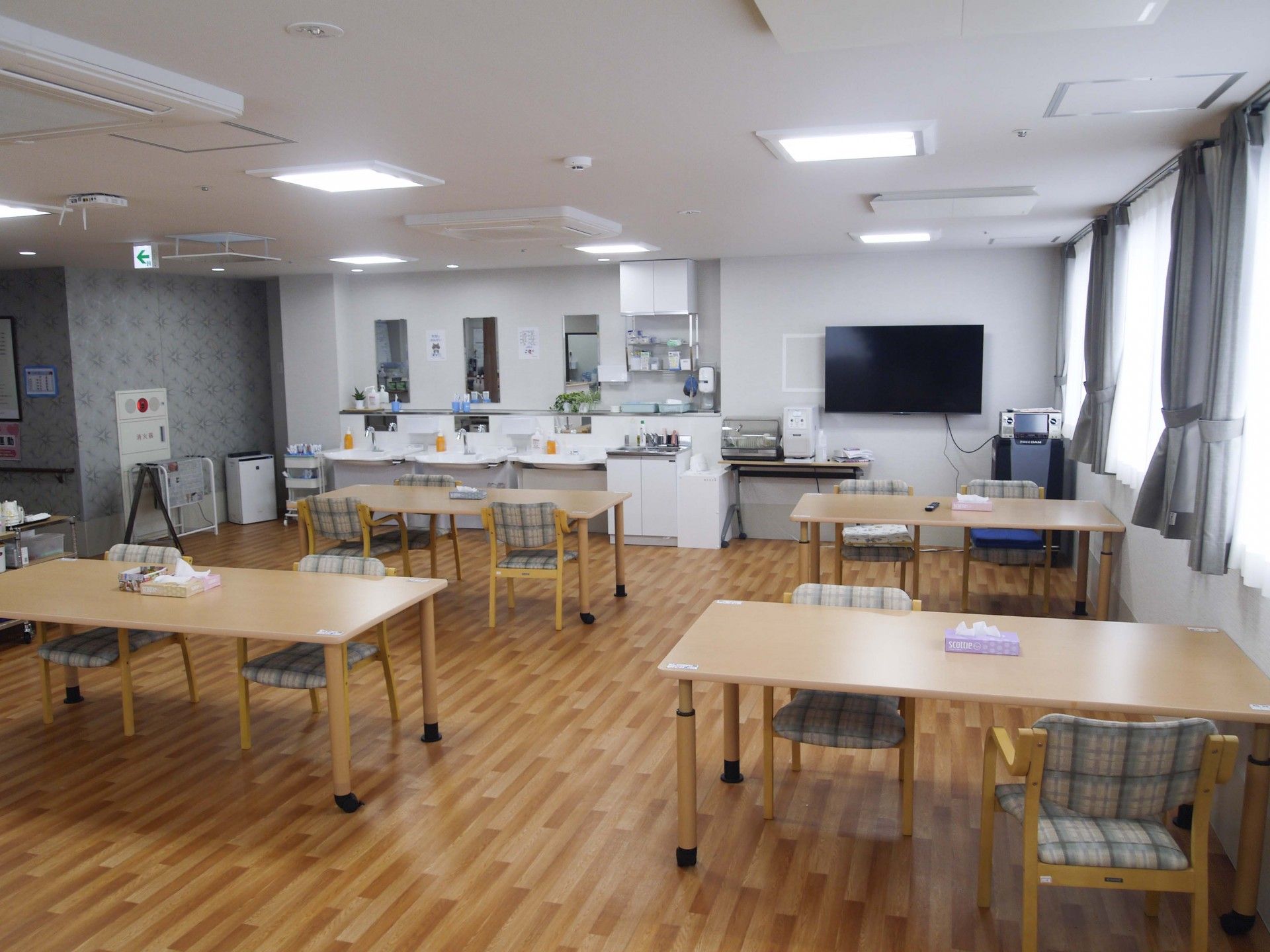 木製のテーブルを囲んで話している白衣を着た男性医師と髪の長い女性。医師はカルテのようなものを見ながら話している。