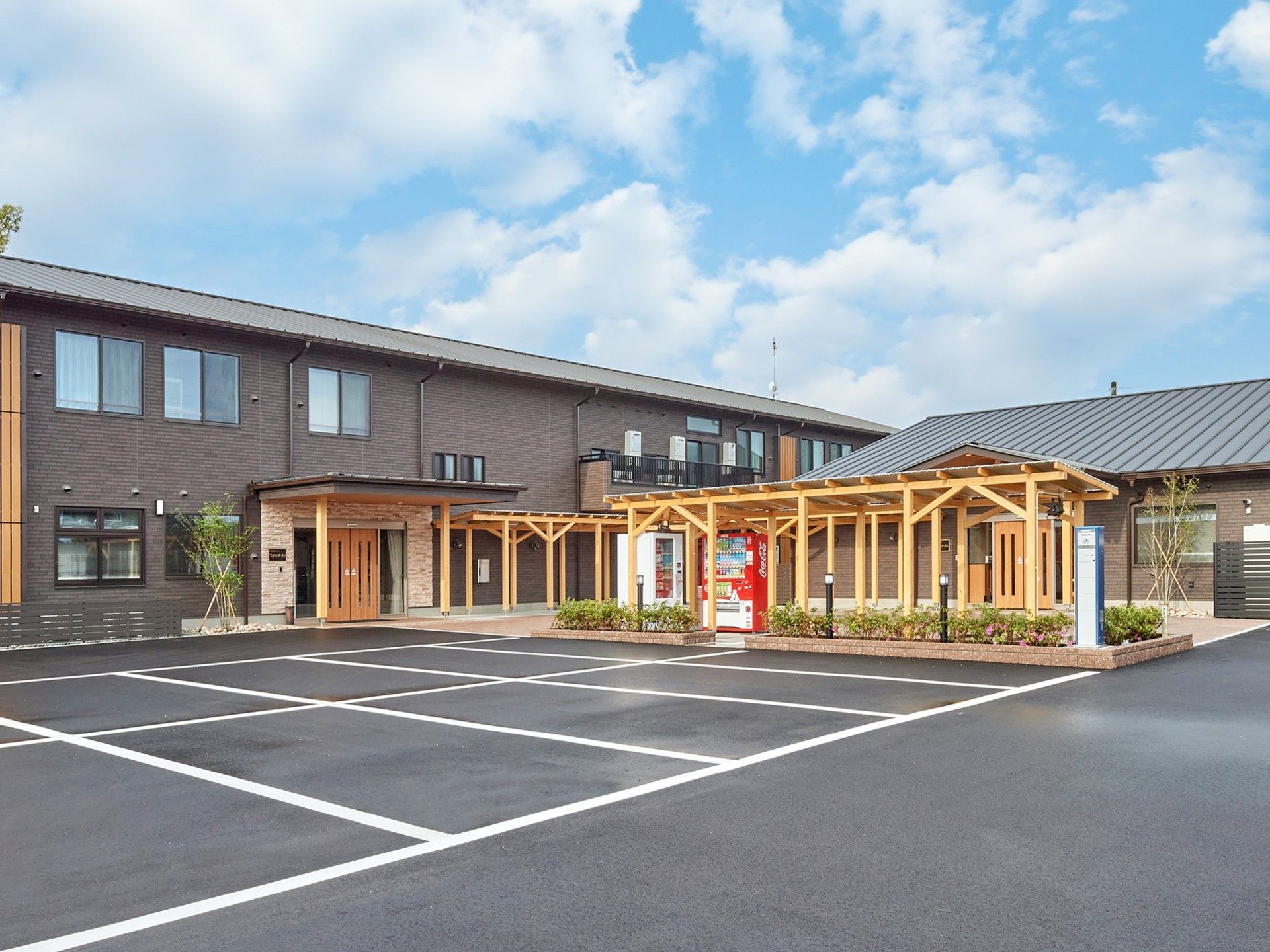2階建ての建物と平屋建ての建物がエル字型に建っていて、敷地内には駐車場もある。