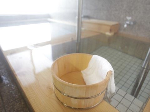 施設の浴室には檜風呂があり、お湯がたっぷりと入れられている。檜の風呂桶には白いタオルがかけられている。