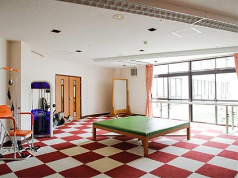 赤色と白色のタイルカーペットが交互に敷かれている。窓際には平行棒、鏡が置かれている。部屋の中央には緑色の大きな台がある。