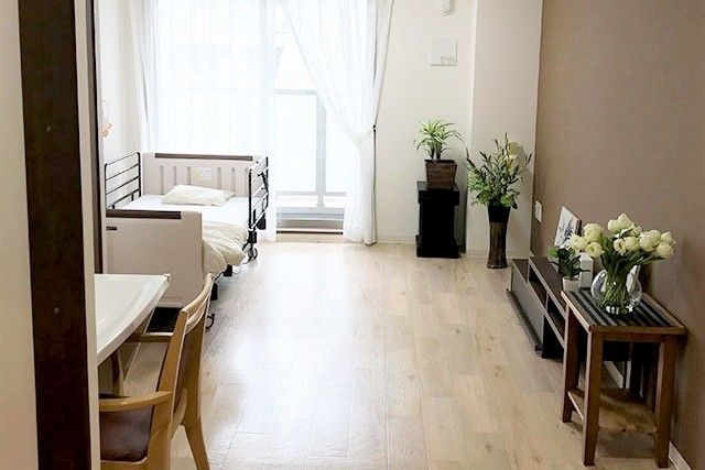 介護用ベッドと収納家具が置かれており、植物が飾られている個室