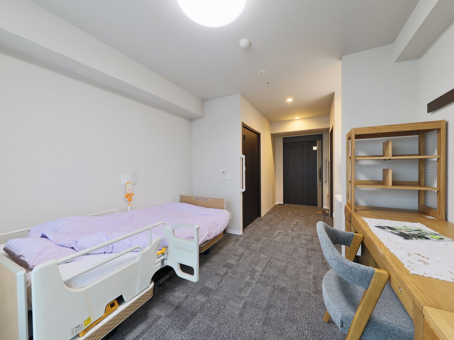 グレーのカーペットが敷かれた部屋には緊急通報装置が設置され、寝具付きのベッドが置かれている。