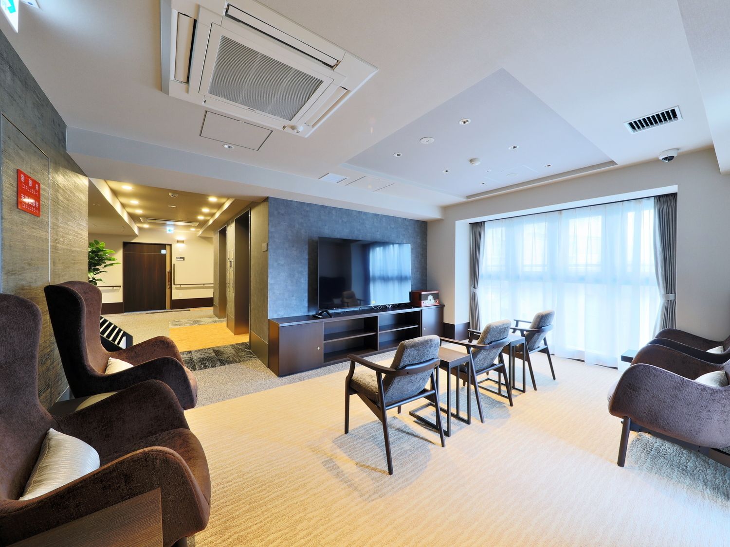 大きな鏡が付いた共有スペースには大型のテレビの前にはいすが複数並んでいてマッサージチェアも複数台置かれている。