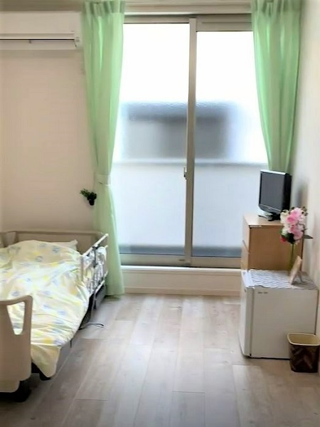 白とダークグレーの２階建ての建物は横に長く、屋外階段も設置されている。