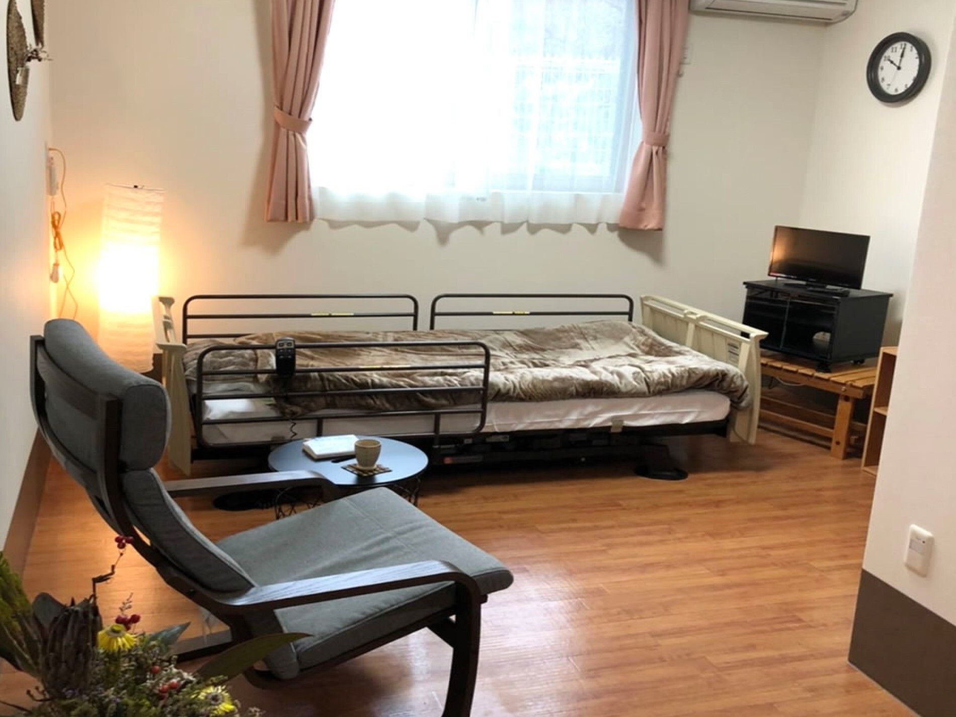 フローリングの部屋には寝具付きのベッドや一人用の椅子、テーブル、和風のライト、テレビなどがある。