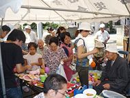 ヨーヨー釣りなどをして楽しんでいる住民の人たち。子供の姿もあり、出店がにぎわっている。