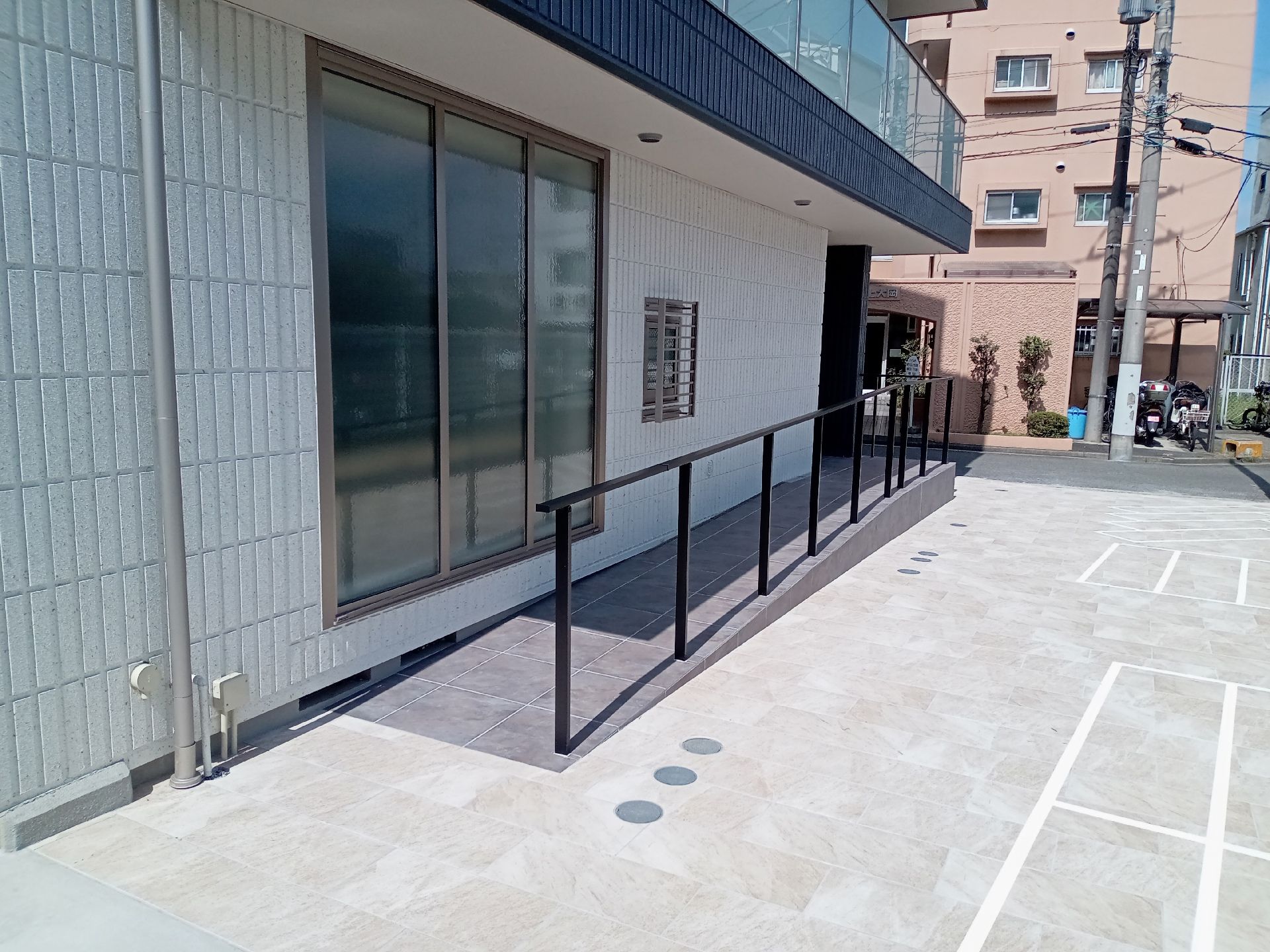 手すり付きのスロープが設置されたエントランス。大きな窓が付いている。