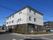 屋外階段が設置された3階建ての建物はベージュとブラウンの外壁で、たくさんの窓が付いている。