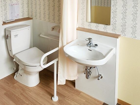 車いす対応の洗面所のそばにはカーテンで開け閉めするタイプのトイレがあり、手すりも付いている。