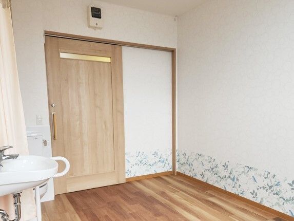 壁の床に近い部分にはリーフ柄の壁紙が貼られ、カーテンで開け閉めするタイプのトイレや洗面所がある。