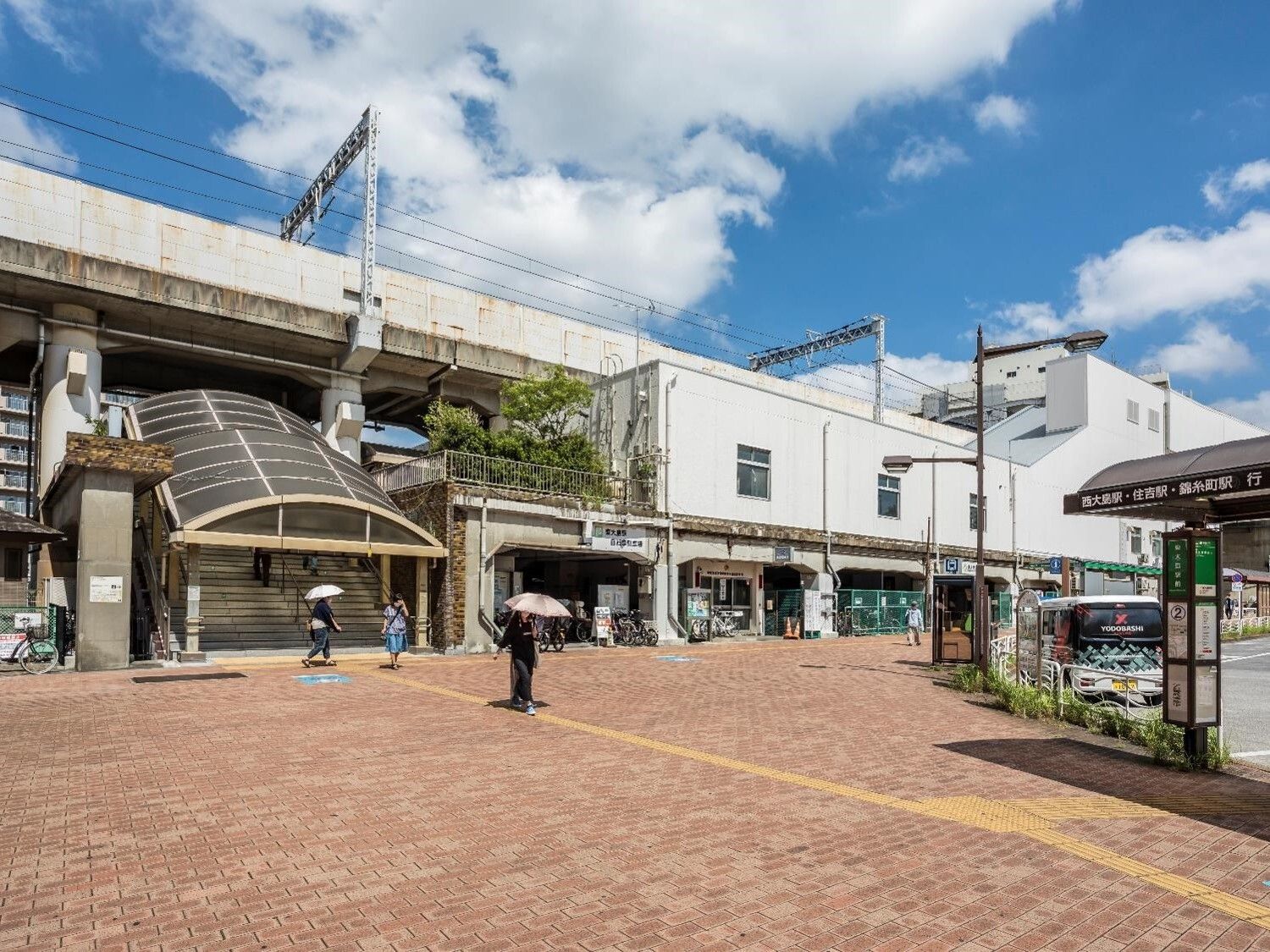 アーケード付きの大きな階段を上り下りして駅構内に入っていく人が数名いる。