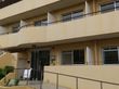 オレンジの外壁の3階建ての建物の玄関には手摺付きのスロープが付いている。