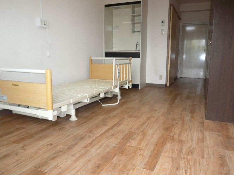 フローリングの部屋には介護ベッドやキッチンがあり、ベッドサイドには緊急通報装置が付いている。