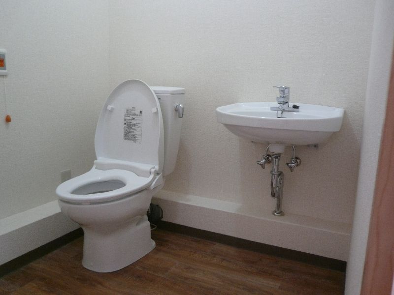 広いトイレ内にはシンプルなデザインの便座が設置されたトイレがあり、手洗い場も付いている。