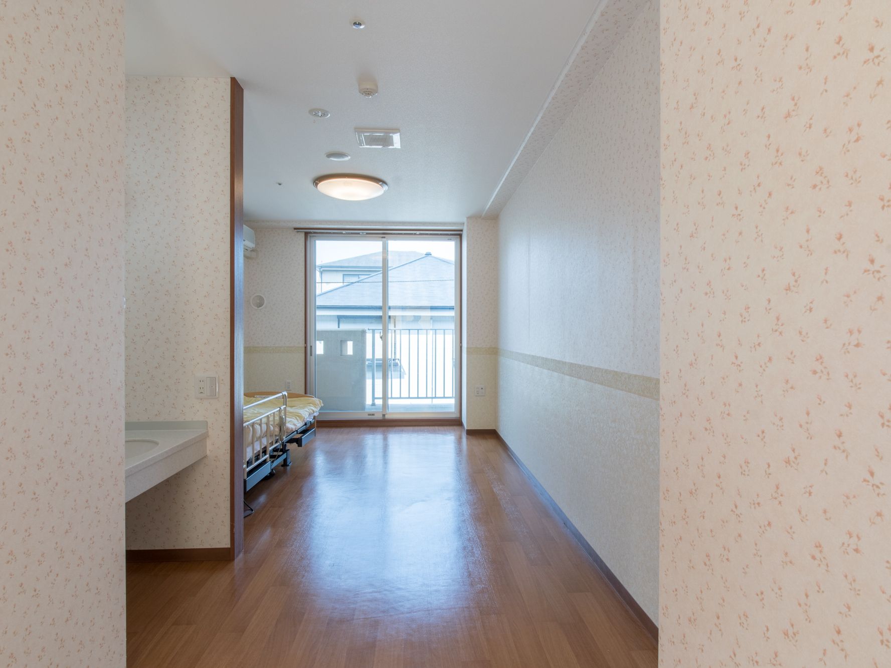 ワンルームタイプの部屋。大きな窓とバルコニーがある、白を基調としていて、部屋全体が明るくなっている。