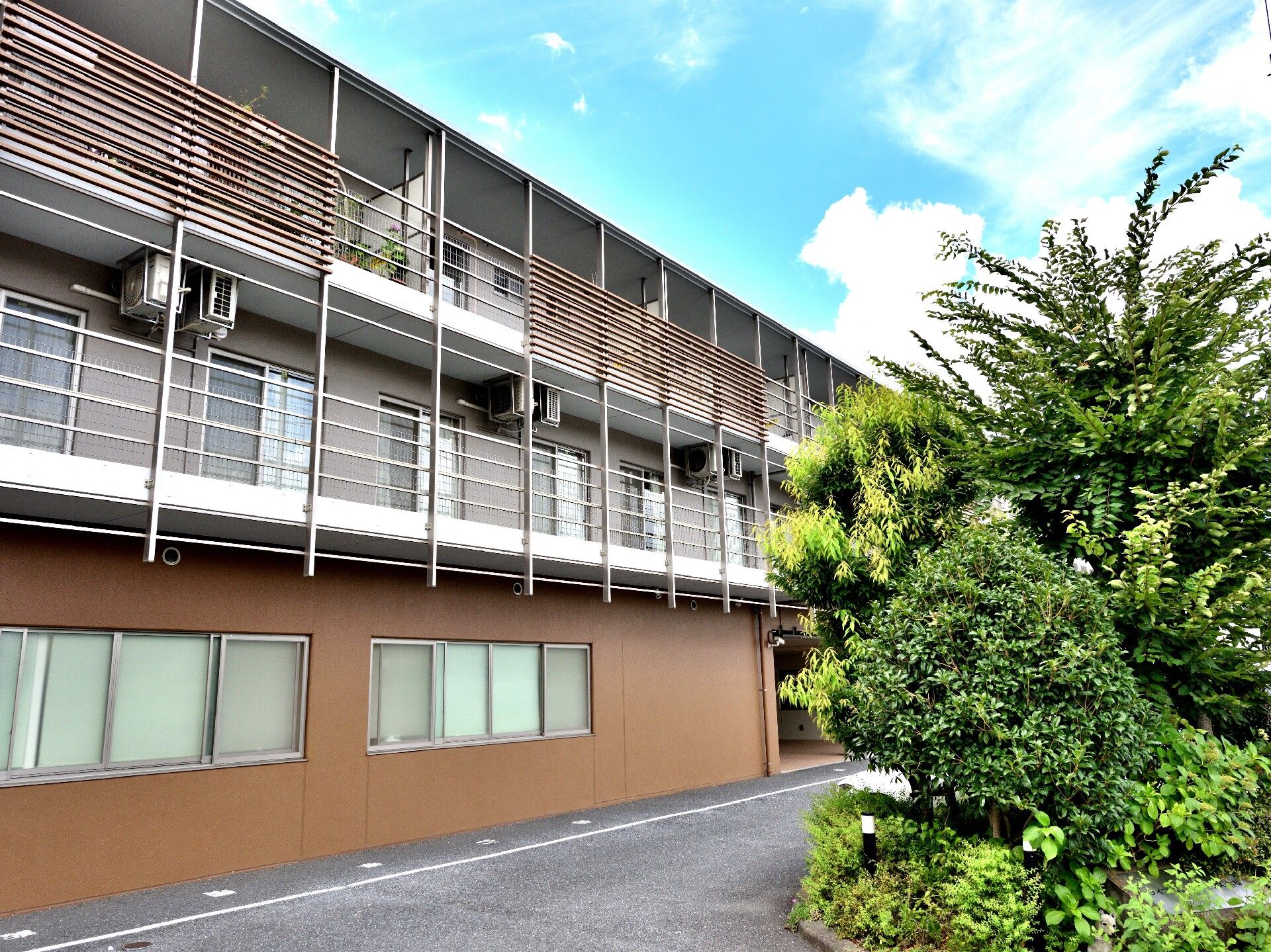 3階建ての建物とその前に植えられたグリーン