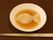 ブラウンのスープの中に浮いている魚の形をしたご飯のようなもの。箸が添えられている。