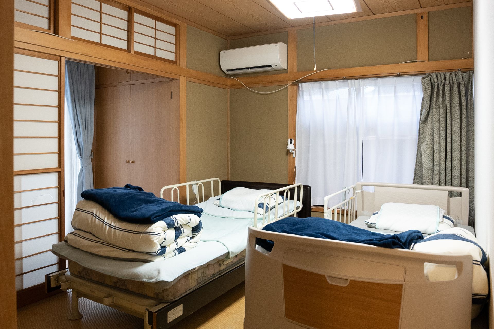眼鏡をかけた高齢女性が笑顔で目の前にいる女性が差し出す手を見ている様子。