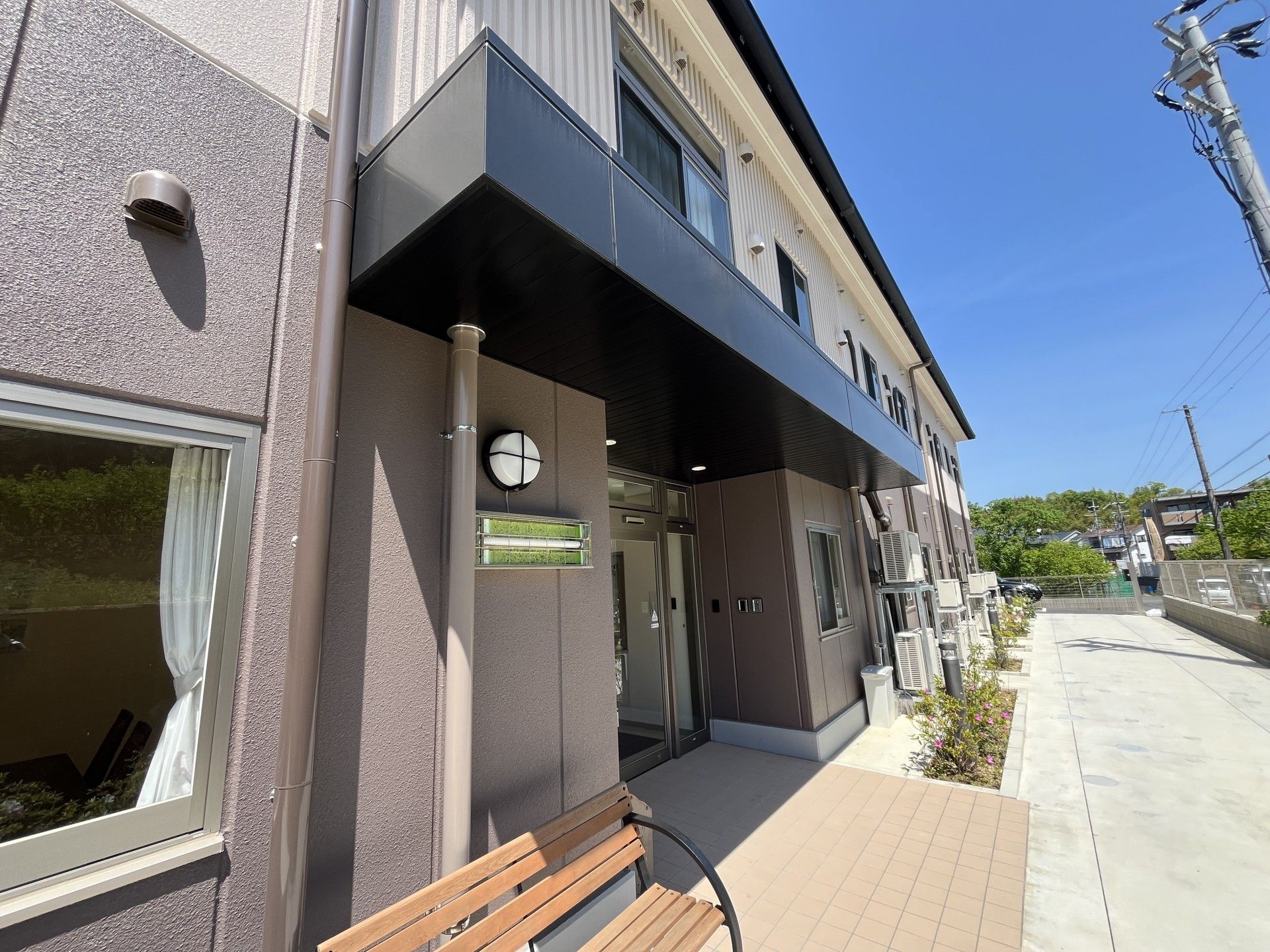 ダークグレーの屋根が付いた２階建ての建物は日当たりがよく、敷地内には駐車場もある。