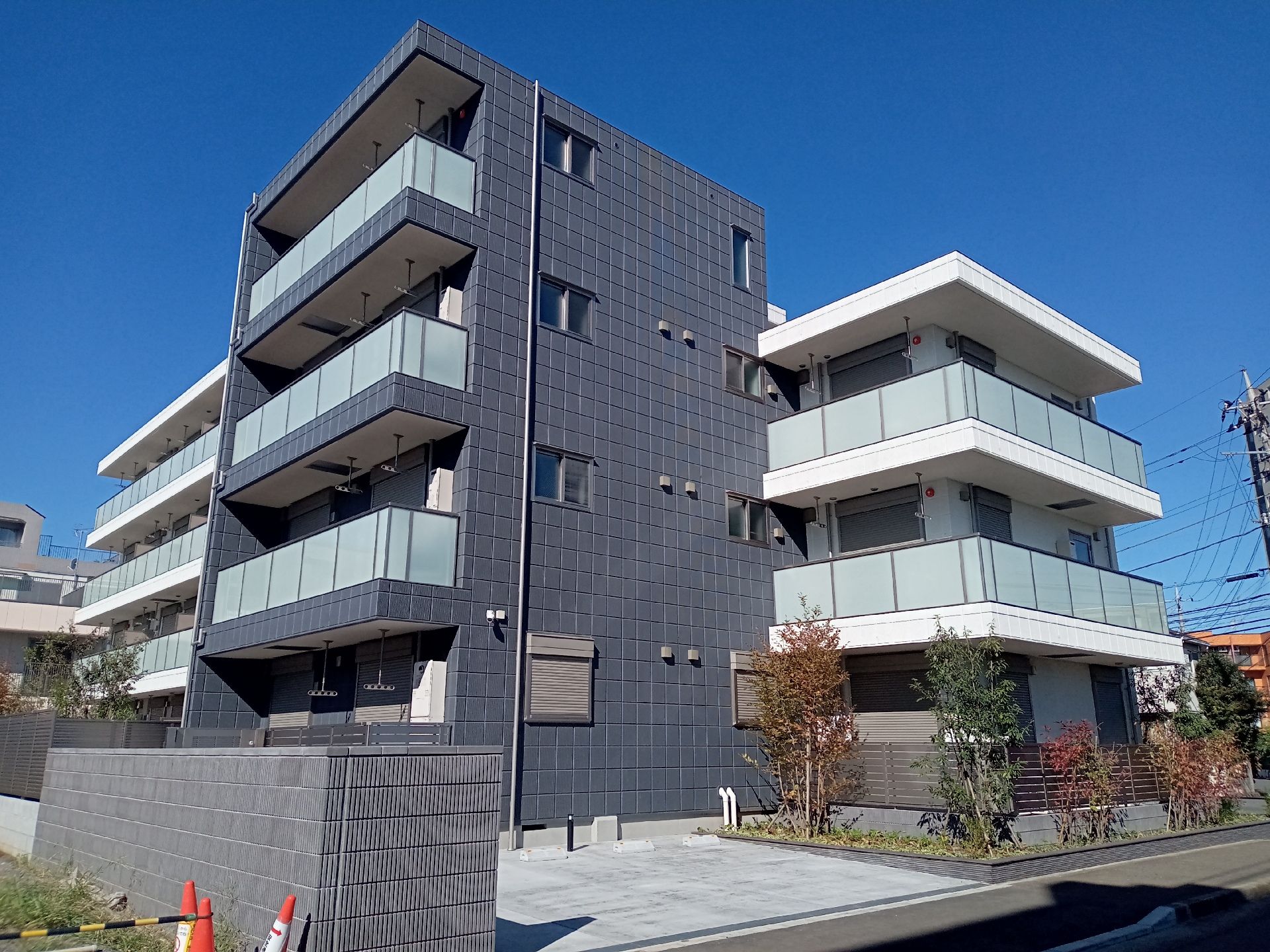 各フロアにベランダが付いた建物は半分がダークグレー、半分が白い外壁で草木が植えられている。