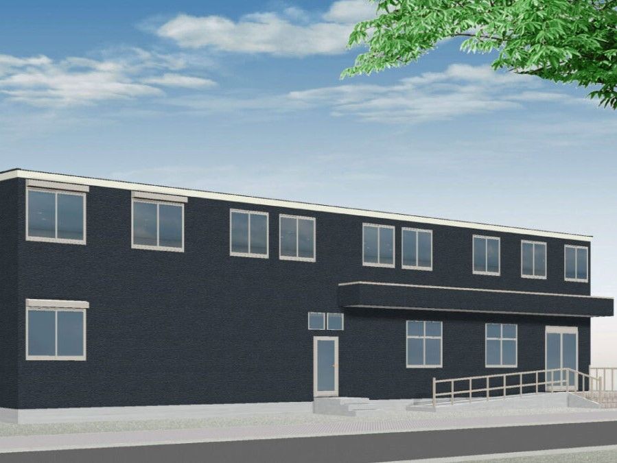 横に長いダークグレーの外観の２階建ての建物は日当たりのいい場所に建っていて、玄関には屋根がある。