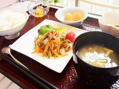 トレーの上にはフルーツや白いご飯、汁物、肉が入った野菜炒め、野菜の小鉢などが並んでいる。