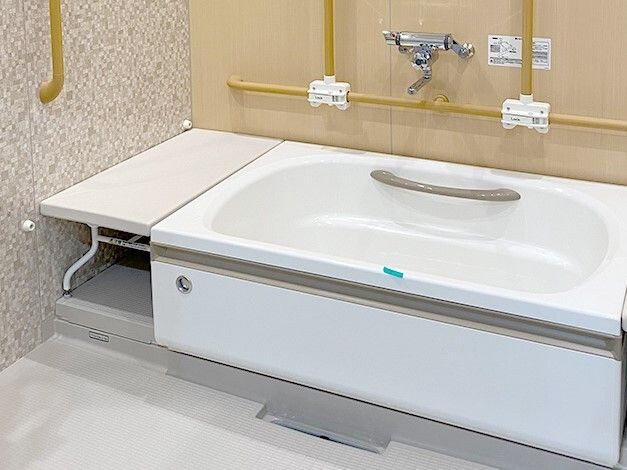 ベンチが付いた一人用の浴槽が設置された浴室にはたくさんの手すりが設置され、安全に配慮されている。