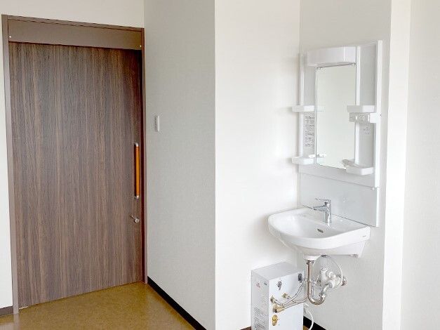 鏡付きの車いす対応の洗面所が付いた部屋にはスライド式のドアが設置され、家具などは置かれていない。
