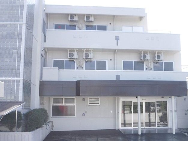 白を基調とした3階建ての建物は横に長く、各フロアにベランダがあり、玄関先には自動ドアが設置されている。