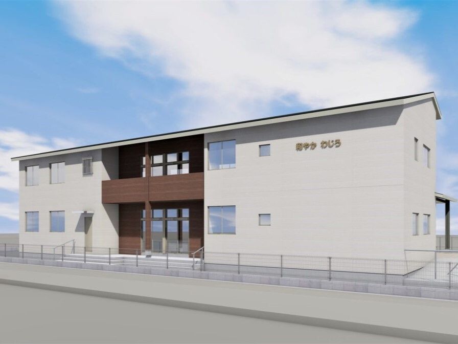 横に長い２階建ての建物は日当たり良好でベージュとブラウンの外壁で周りにはフェンスがある。