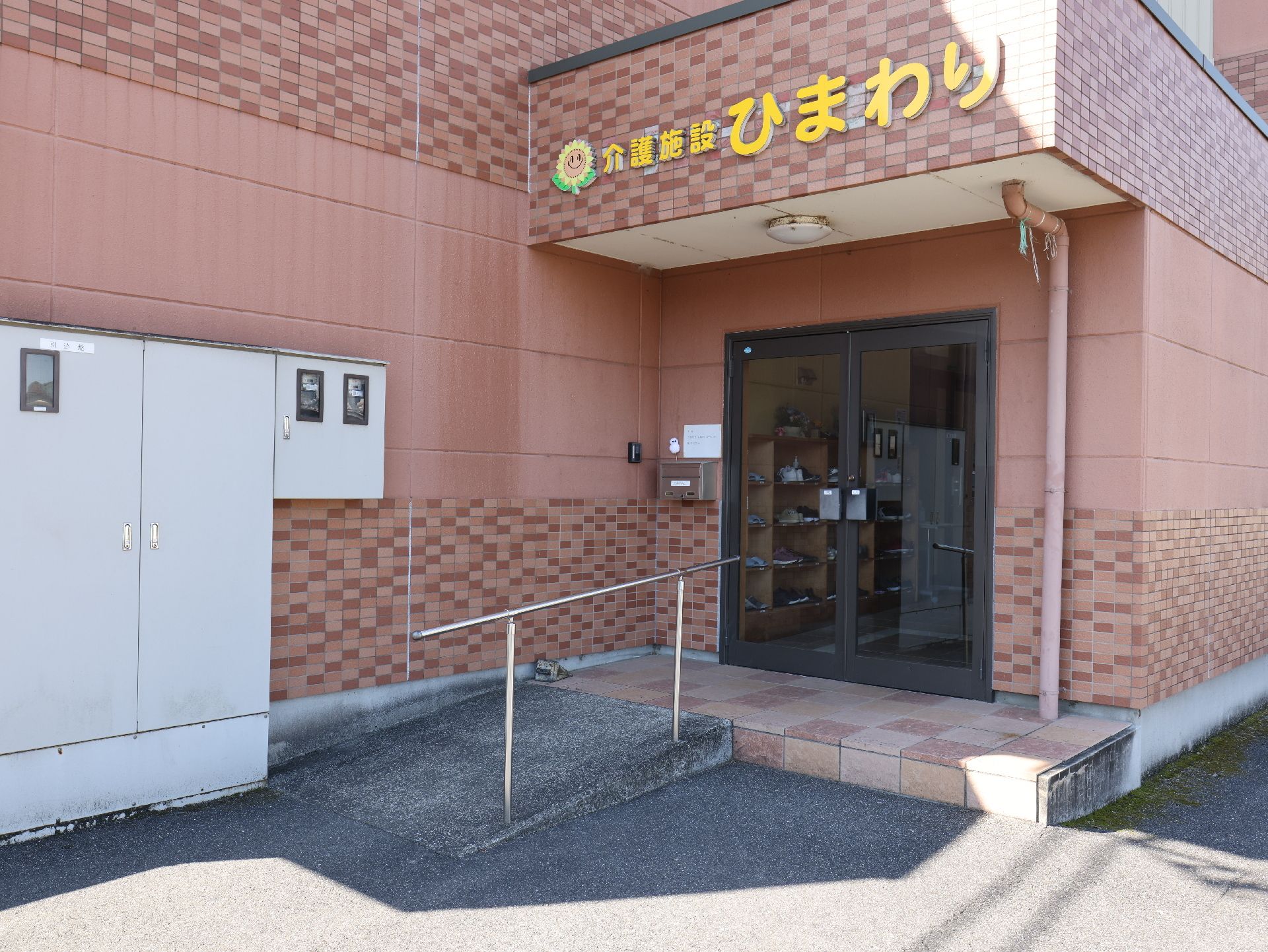 真剣な表情で話しているエプロンを付けた若い女性スタッフとカーディガンを着た高齢女性。スタッフはカルテを持っている。