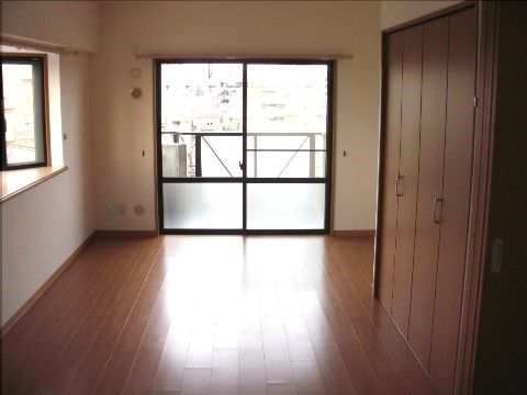 掃き出し窓と腰高窓の二面採光の部屋。折り戸扉のクローゼットがあり、床や扉は少し濃いめの茶色で落ち着きがある。