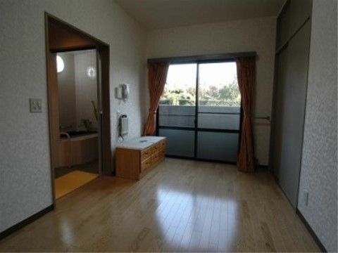 掃き出し窓の外にはベランダがある。薄い色のフローリング敷で壁はクリーム色。壁を隔てたところに浴室が見える。