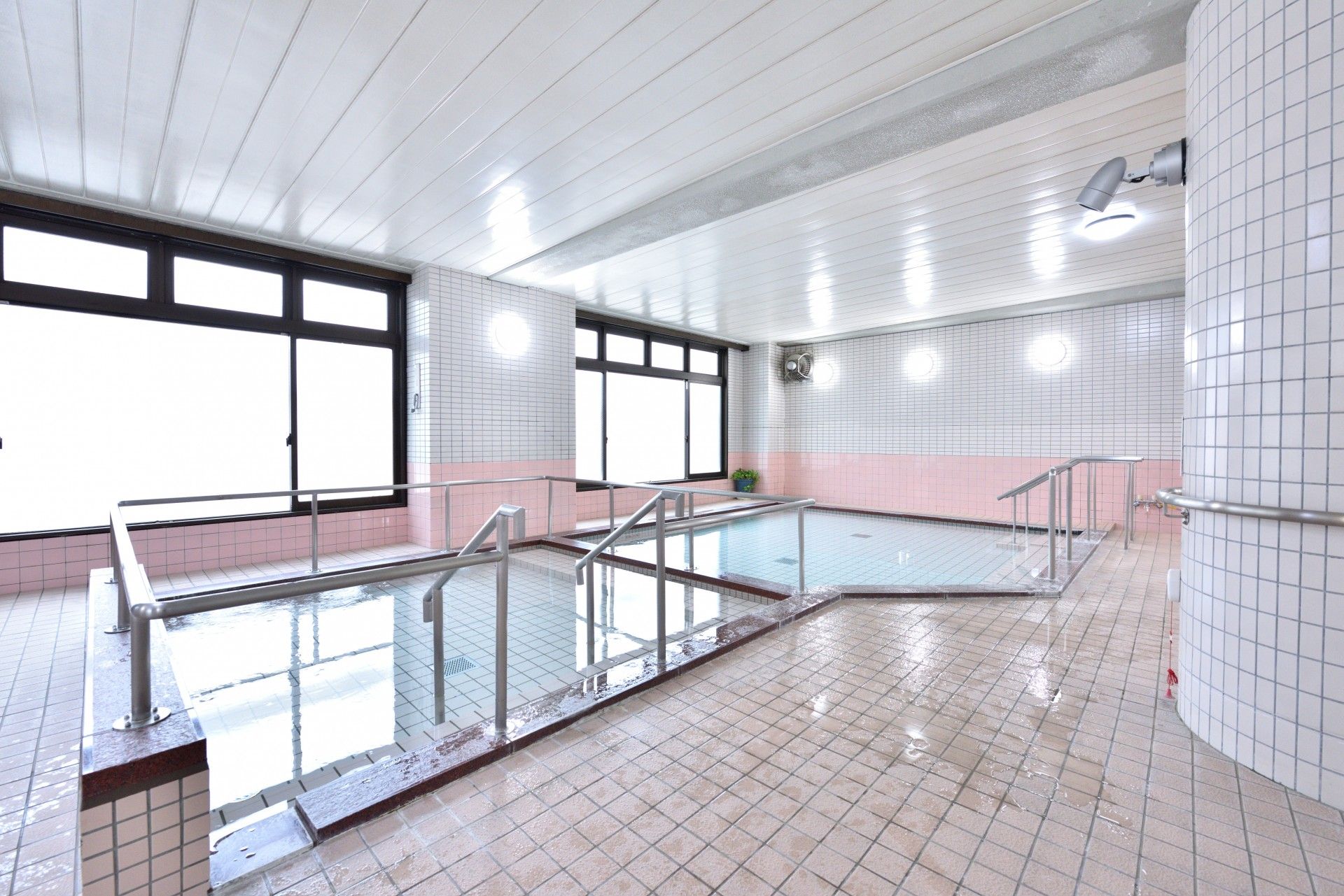 大きな窓から自然光の入るテーブルセットとベッドが設置された居室