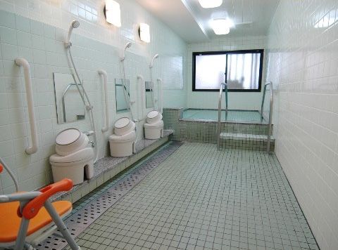 タイル張りの広々とした浴室で、洗い場が複数備わっている。浴室の出入口に段があるが、手すりが設置されている。