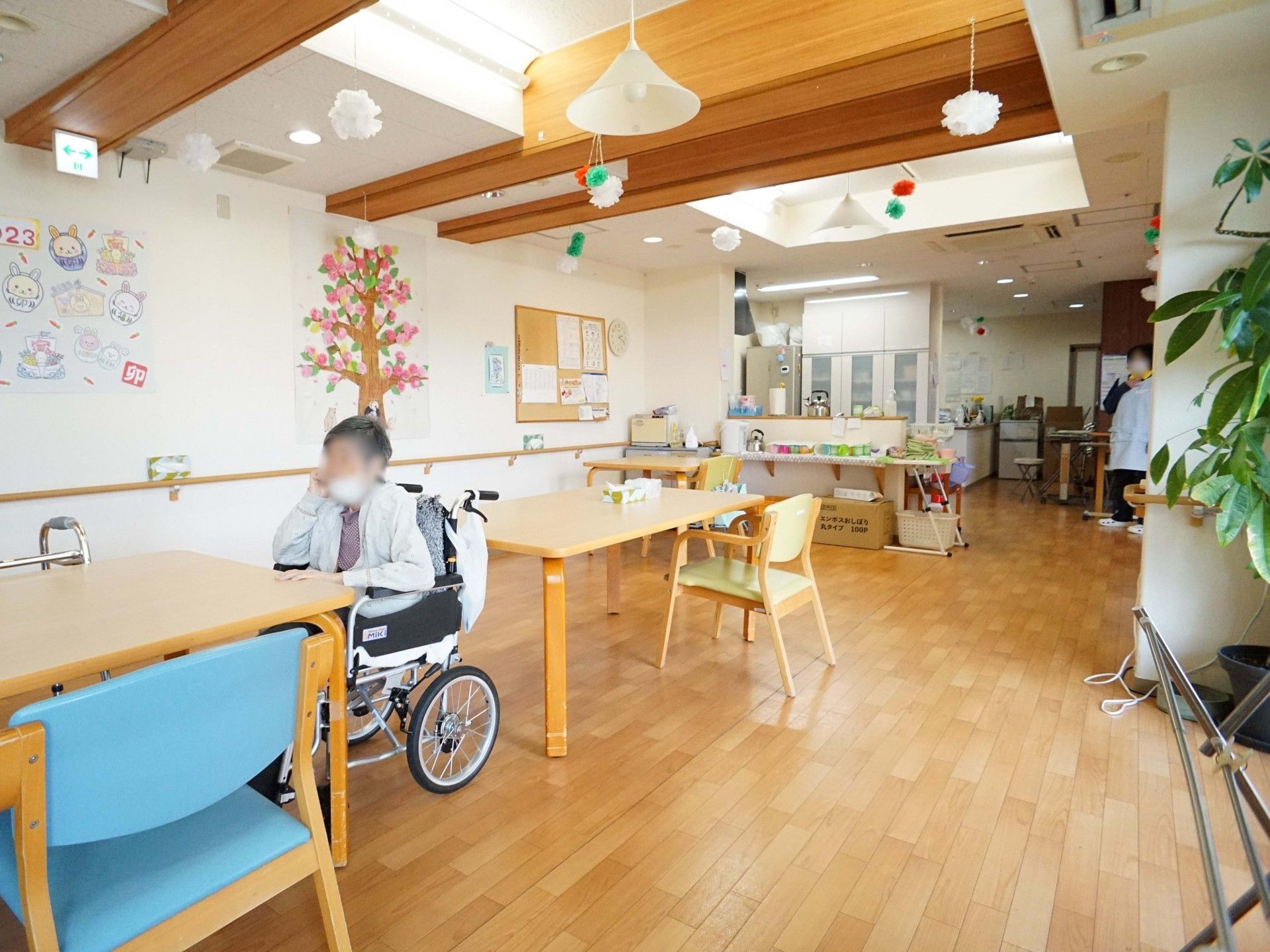大勢のエプロンを付けた女性スタッフと男性スタッフが建物の前に並び、ほほえみを浮かべている。