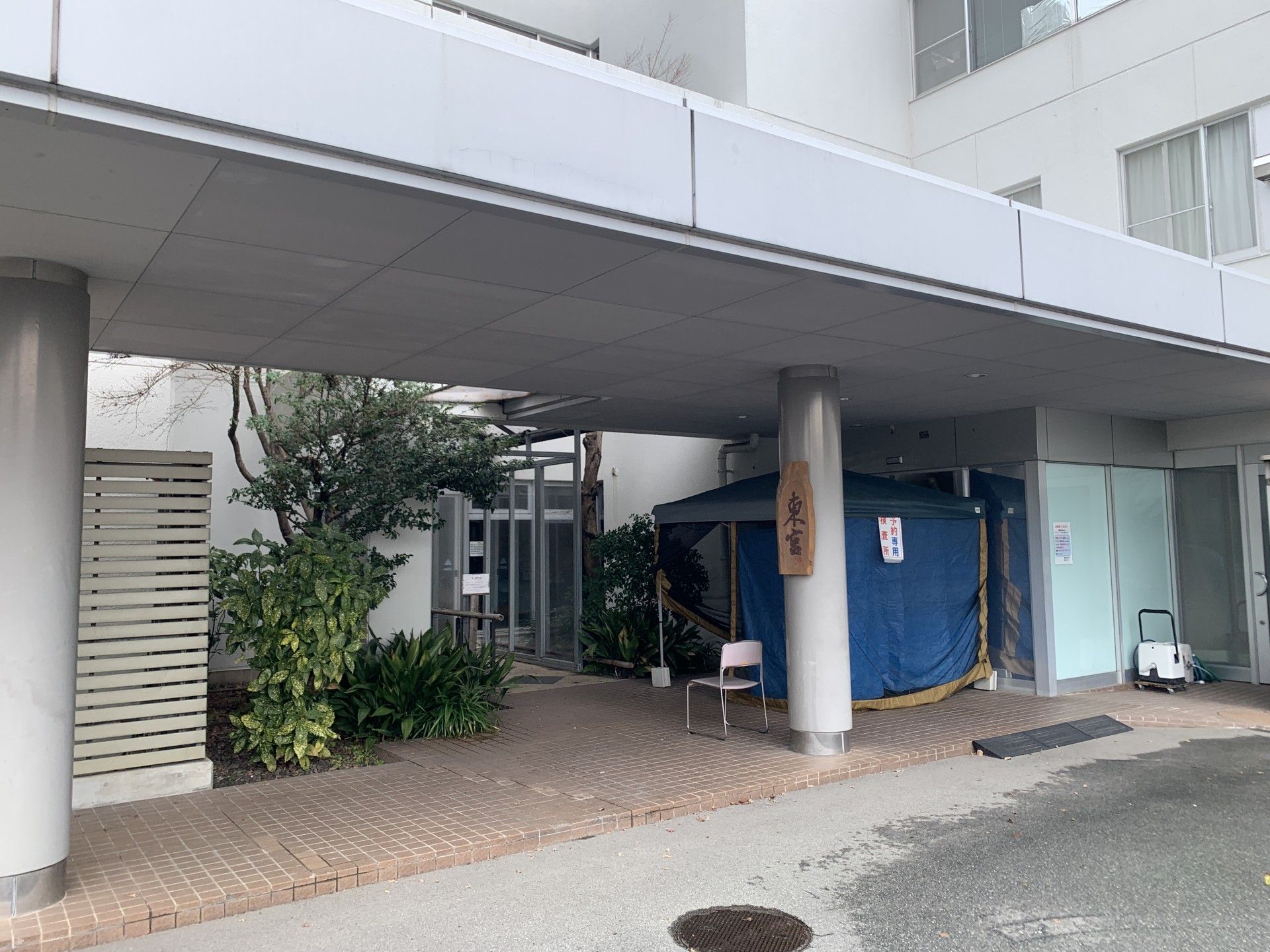 笑顔で高齢男性の介助に当たるブルー系のエプロンを付けた女性スタッフ。