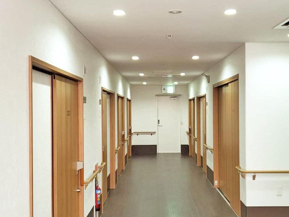 手すりがたくさん付いた廊下はまっすぐで幅が広く、消火器も置かれている。